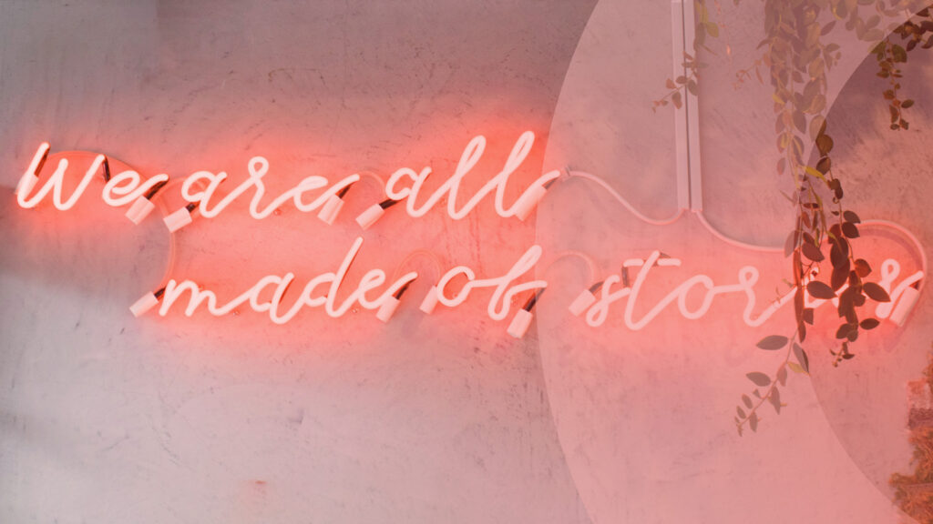 Text i neon på en vägg: "We are all made of stories."