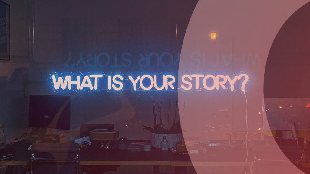 En neonskylt med texten "What is your story?" i ett fönster till ett kontor.