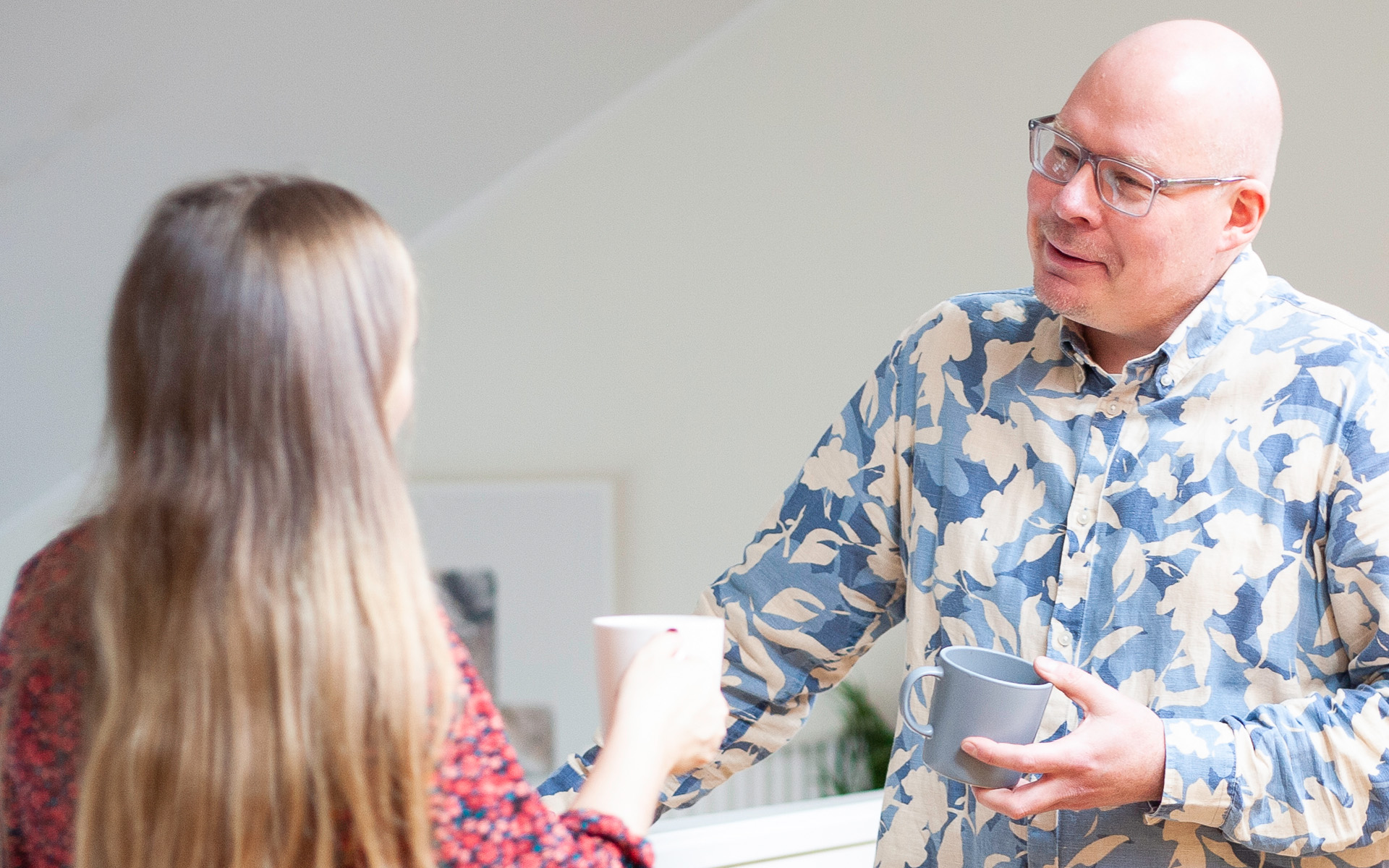 Två kollegor på en strategisk webbyrå konverserar över en kopp kaffe.