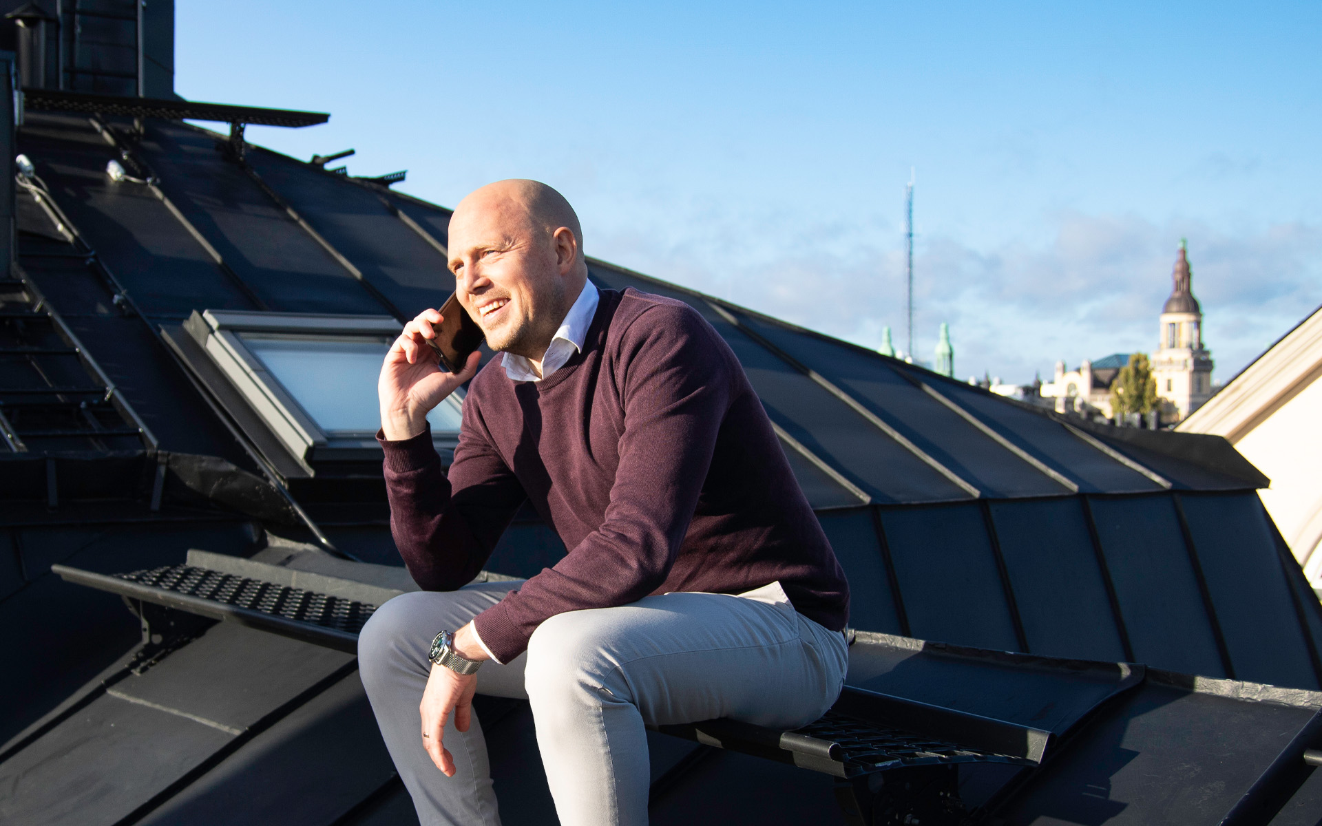 En man sitter på ett hustak vid Kungsholmstorg och pratar i mobiltelefon.