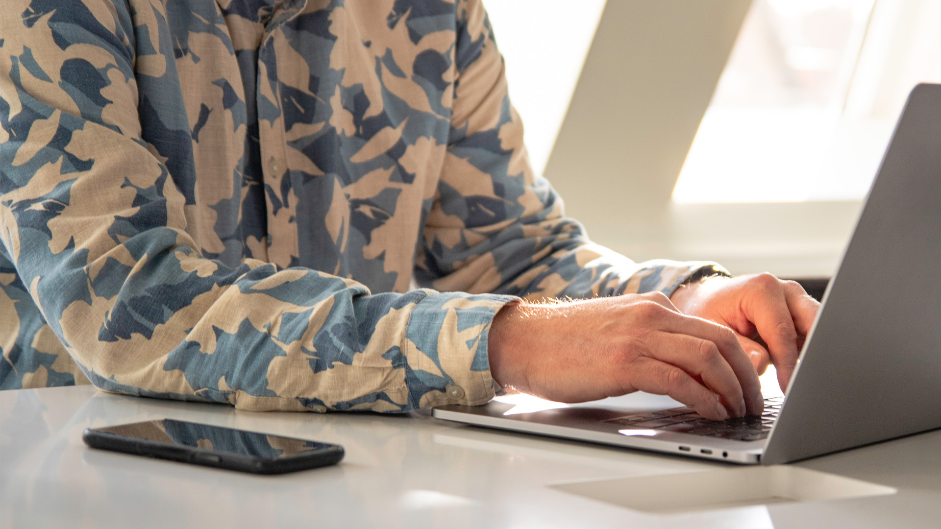 En anställd på en webbyrå sitter vid en laptop och jobbar med innehållet på en webbplats.