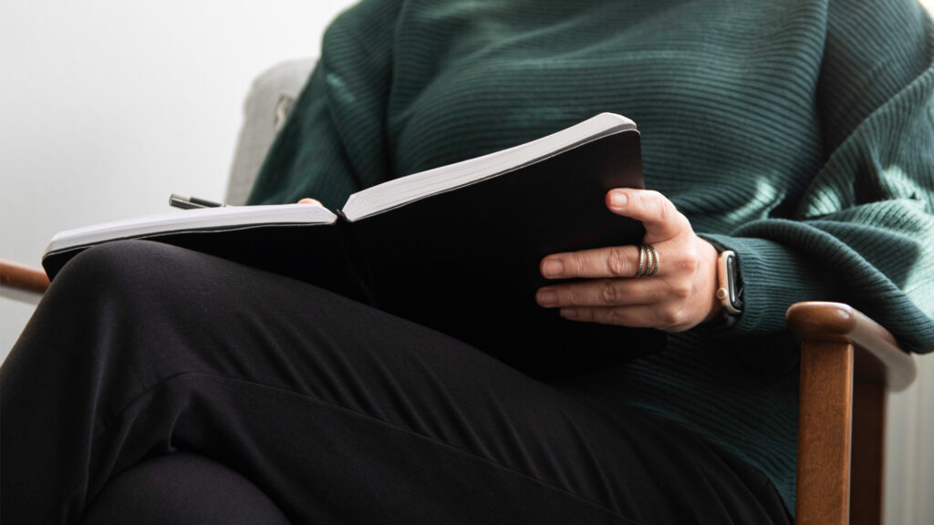 Person som sitter med ett anteckningsblock och arbetar med en digital brief inför ett projekt att bygga om företagets webbplats.