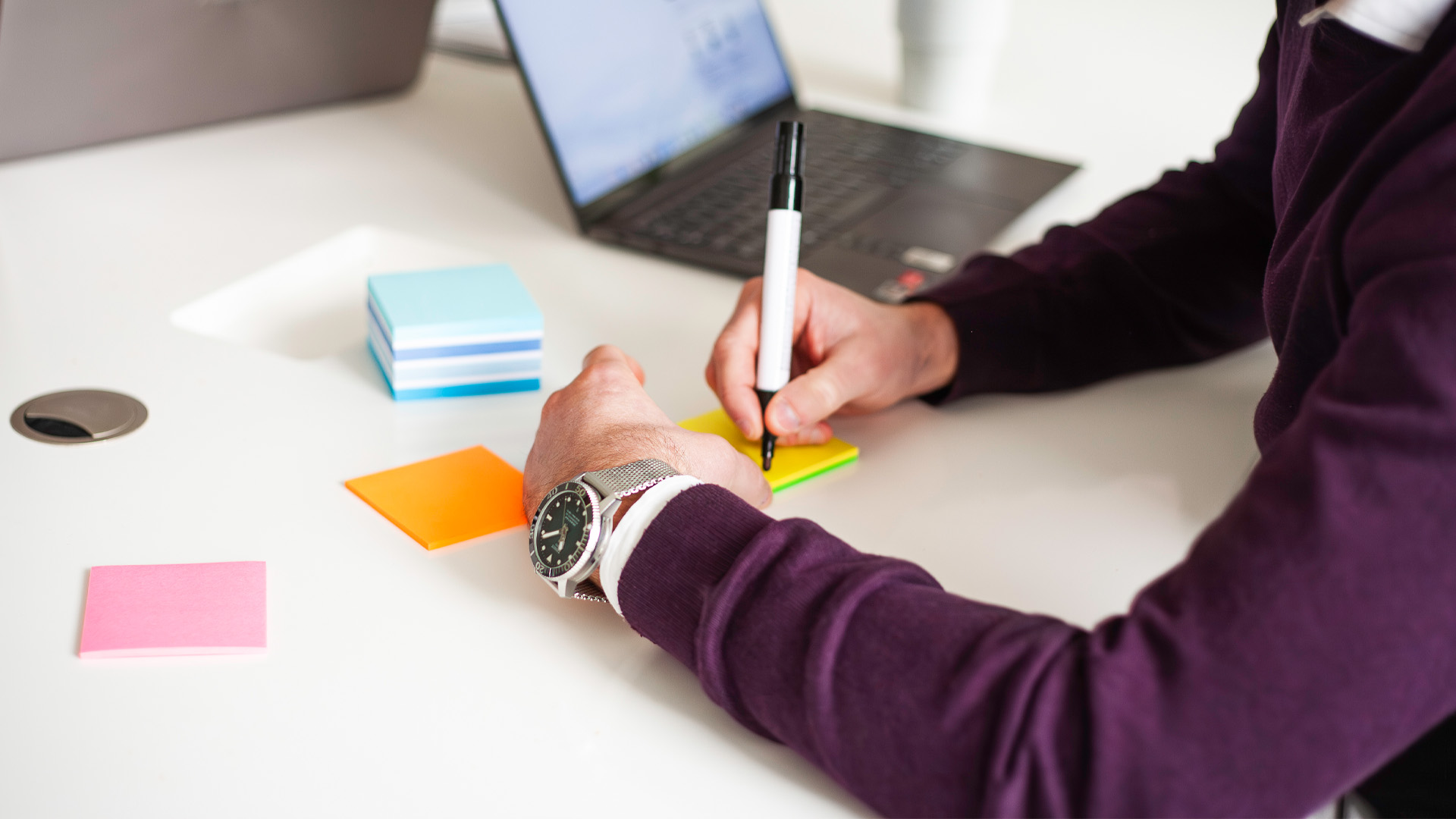En person som börjar skriva en digital brief på postit-lappar.