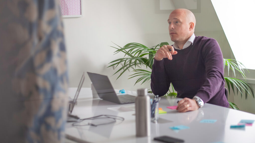 Ett mötesrum under en workshop. I fokus en person som tittar upp från sin laptop.