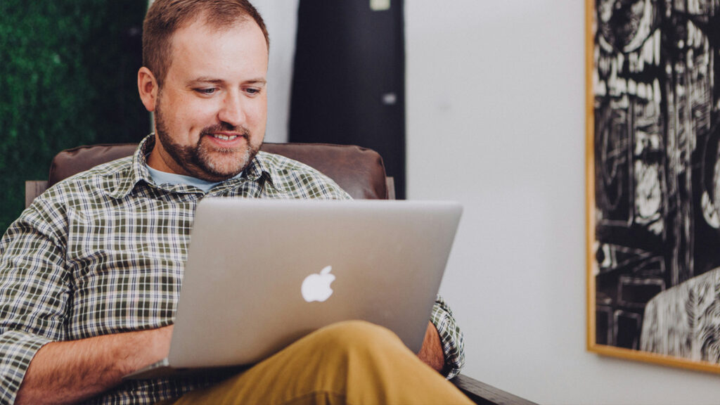 En person som sitter med laptop i knät.