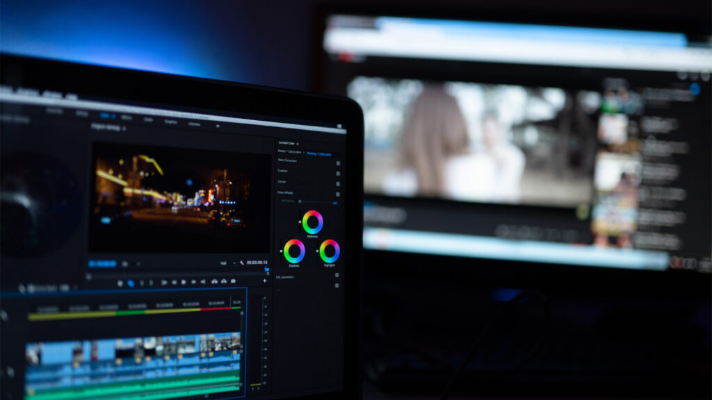 Videoredigeringsverktyg i en laptop och på en större datorskärm i bakgrunden syns YouTubes gränssnitt
